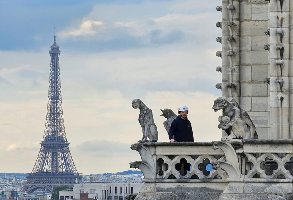 Mathieu Houlbert entre deux gargouilles sur le beffroi sud de Notre-Dame.