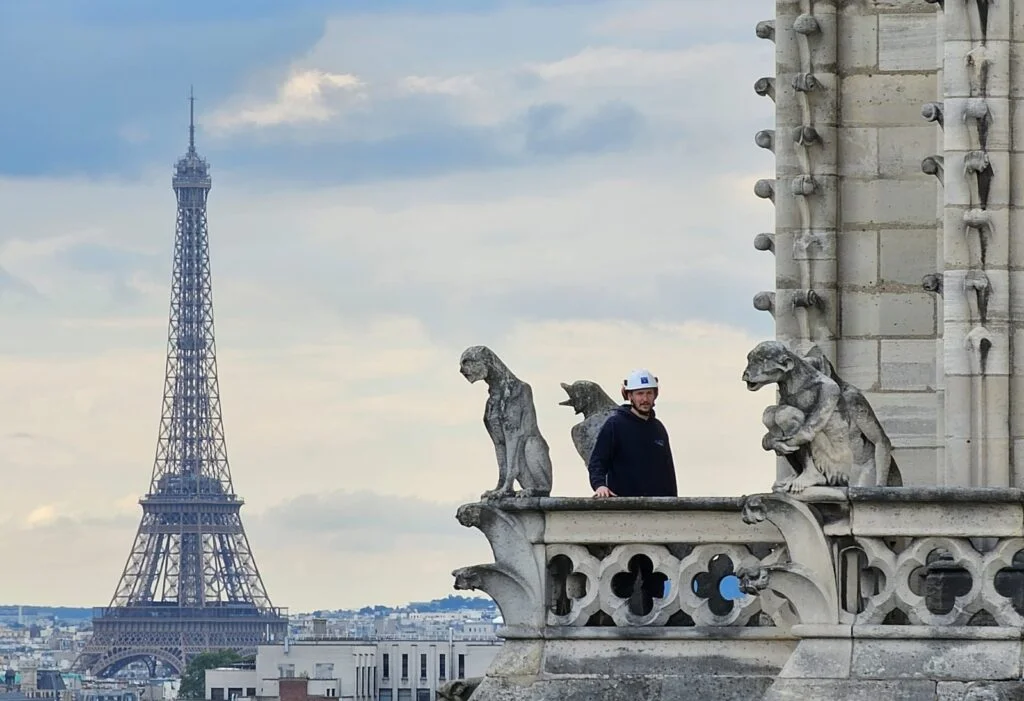 Mathieu Houlbert entre deux gargouilles sur le beffroi sud de Notre-Dame.