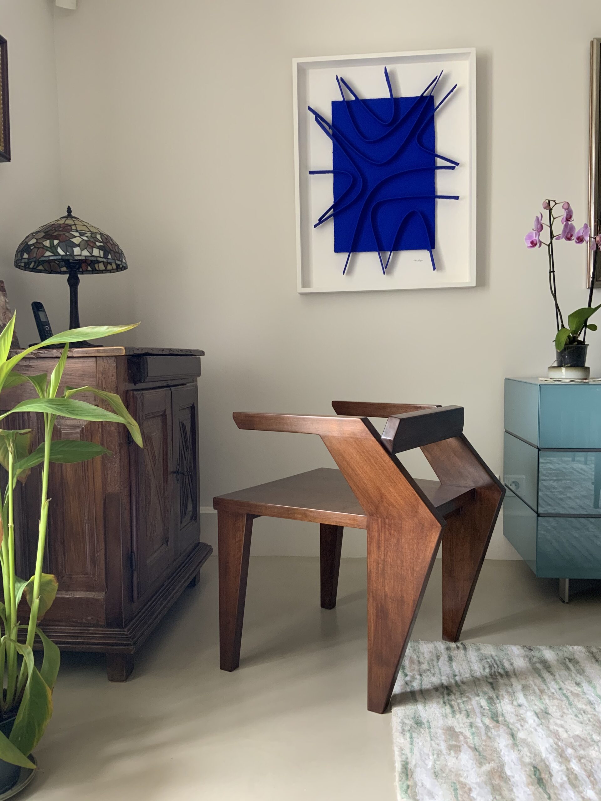 Salon avec Fauteuil en noyer, buffet, une lampe un tableau bleu.