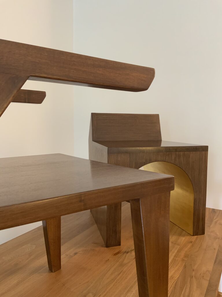 Vue de coté du Fauteuil Référence R121 en bois massif de noyer. Un autre fauteuil à la feuille d'or se trouve derrière.