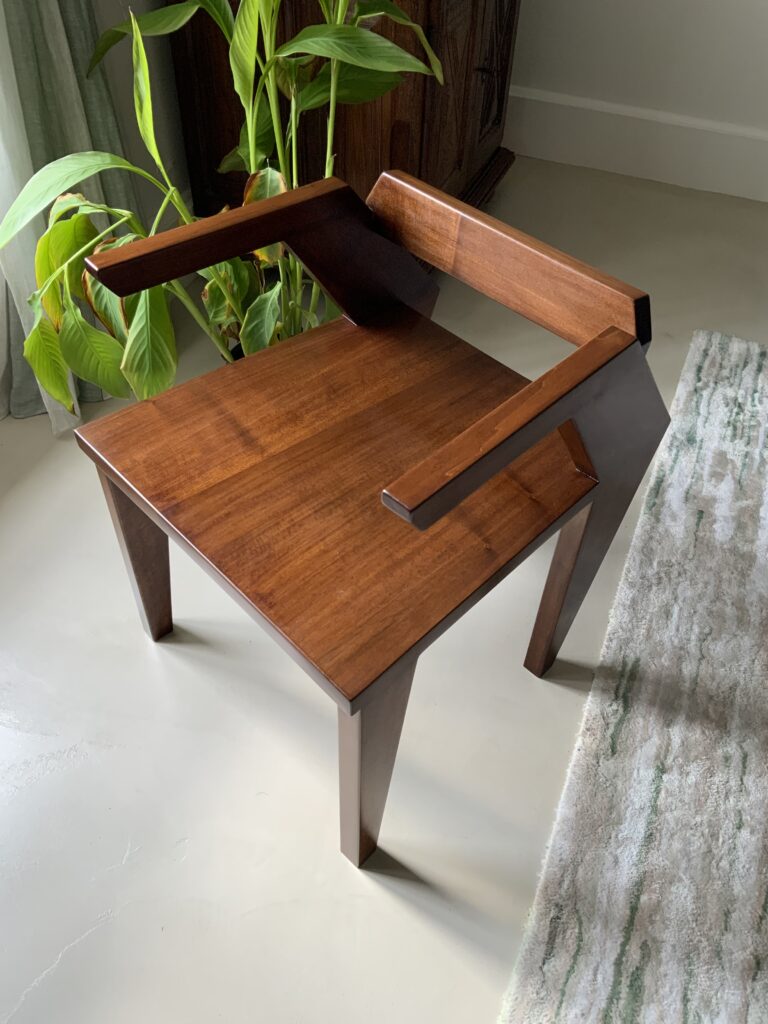 Fauteuil Référence R121 en bois massif de noyer. Plante verte derrière. Mobilier contemporain en série limitée 8+4. Vue de haut