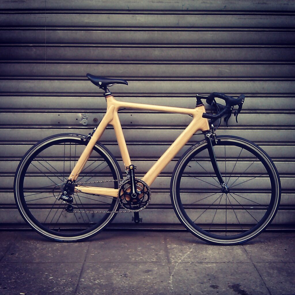 Vélo en bois frêne sur trottoir devant un rideau de fer.
